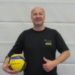 Porträt Florian Leitenberger, junger Mann mit wenig Haaren, im schwarzen T-Shirt und Volleyball in der Hand