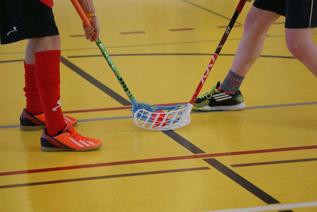 Zwei Personen, die beim Bully bei einem Floorballspiel stehen