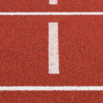 Eine Kunststoffbahn in der Farbe rot, dazu Markierungen für Läufer mit der Startnummern 5