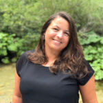 Porträt Kerstin Haase, junge hübsche Frau mit langen brauen Haaren und einem schwarz Top