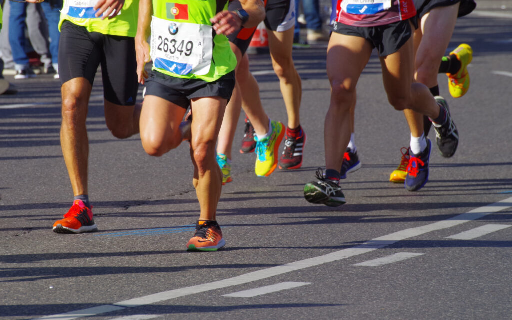 Einige Personen, von denen man nur die Beine und die Oberkörper sieht, die einen Marathon laufen