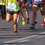 Einige Personen, von denen man nur die Beine und die Oberkörper sieht, die einen Marathon laufen