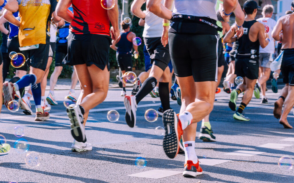 Viele Personen, von denen man meistens nur die Beine und die Oberkörper sieht, die einen Marathon laufen
