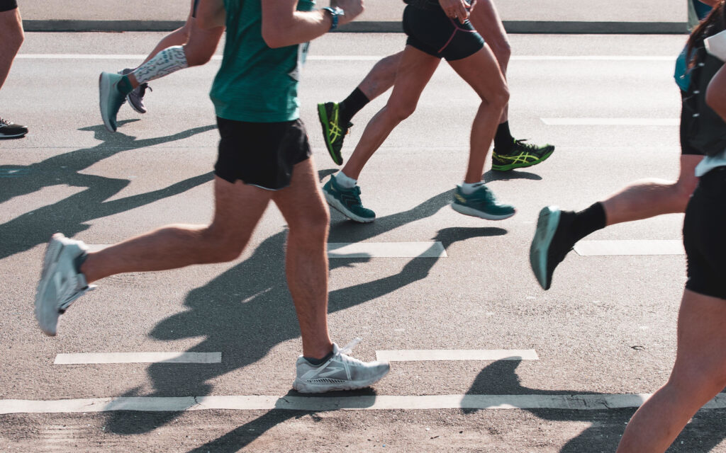 Einige Personen, von denen man nur die Beine und die Oberkörper sieht, die einen Marathon laufen