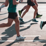 Einige Personen, von denen man nur die Beine und die Oberkörper sieht, die einen Marathon laufen