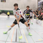 Mehrere Junge Männer einem Floorballspiel, dazu im Hintergrund Zuschauer