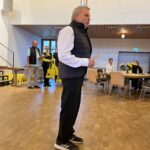 Ein Mann hält eine Rede, im Hintergrund weitere Personen