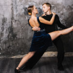 Ein junges Tanzpaar zeigt eine Tanzfigur und schaut sich damit tief in die Augen