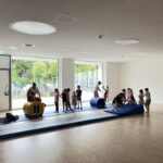 Zwei Übungsleiterinnen, die Kindern auf Matten Bodenturnen beibringen