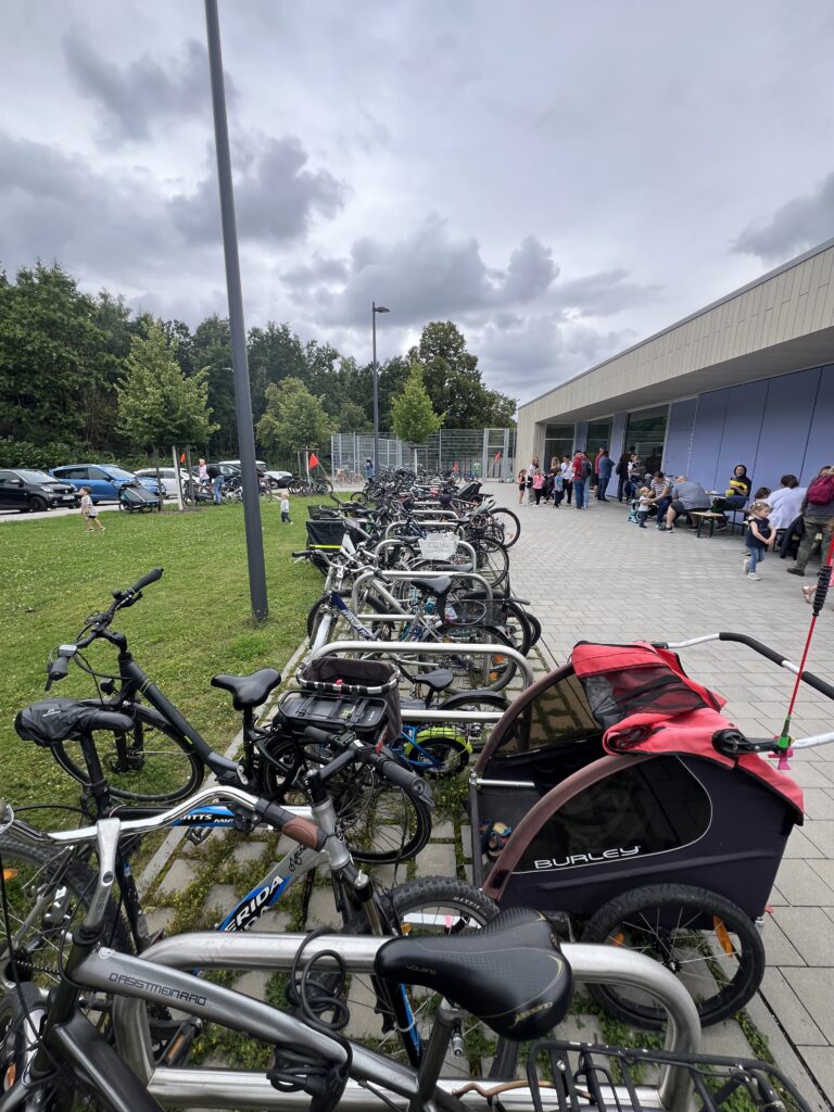Ein Fahrradparkplatz mit vielen Fahrrädern vor einer Sporthalle