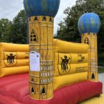 Ein Hüpfburg mit roten Boden, gelben Wänden und blauen Türmen