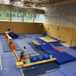 Eine Sporthalle mit einem Hindernisparcour, dazu viele kleine Kinder und einige Eltern