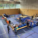 Eine Sporthalle mit einem Hindernisparcour, dazu viele kleine Kinder und einige Eltern