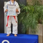 Ein Mädchen auf einem Podest in einem Karateanzug, der eine Urkunde in ihrer Hand hält