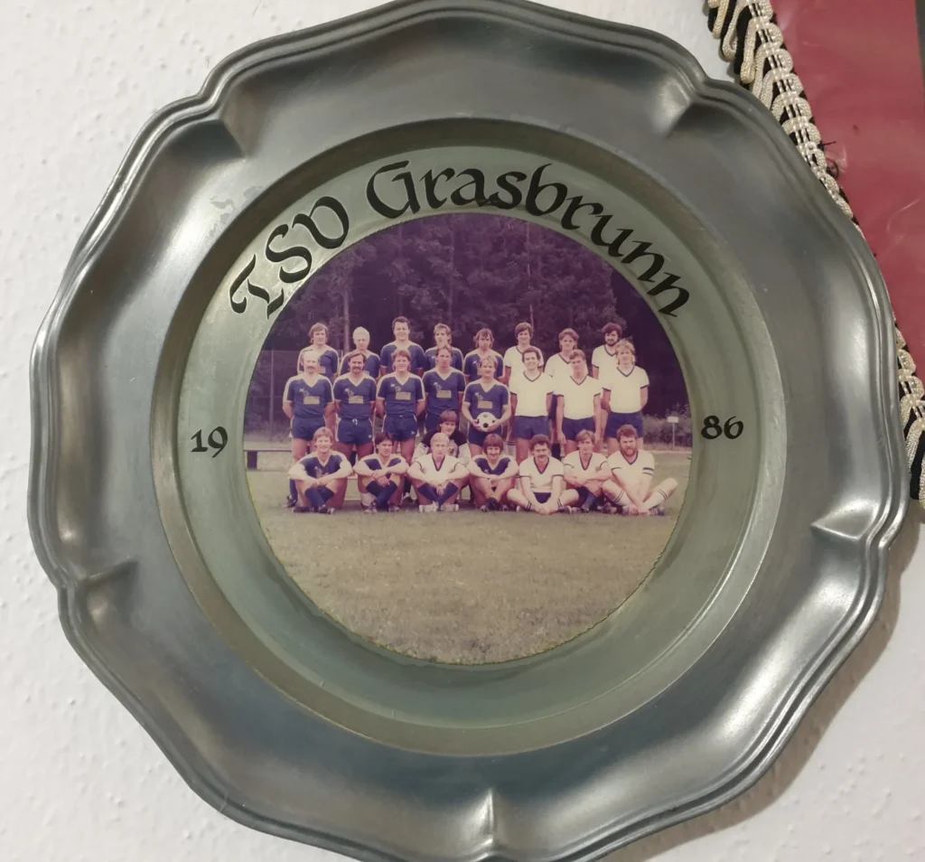 Ein Teller aus Blech, welcher an einer Wände hängt und ein Mannschaftsfoto zeigt