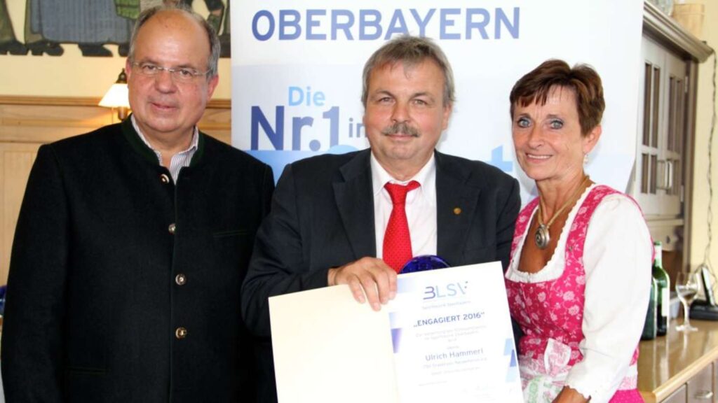 Drei Personen, einem wird eine Urkunde überreicht