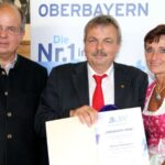 Drei Personen, einem wird eine Urkunde überreicht