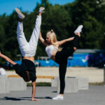 Zwei Jugendliche, ein Mädchen macht eine Kunstfigur, der Junge einen Handstand auf einem Arm