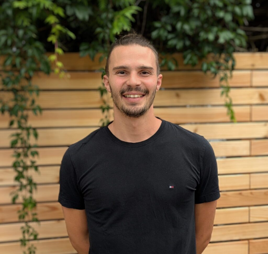 Porträt Sebastian Zinsmeister, junger Mann mit braunen Haaren und einem schwarzen T-Shirt